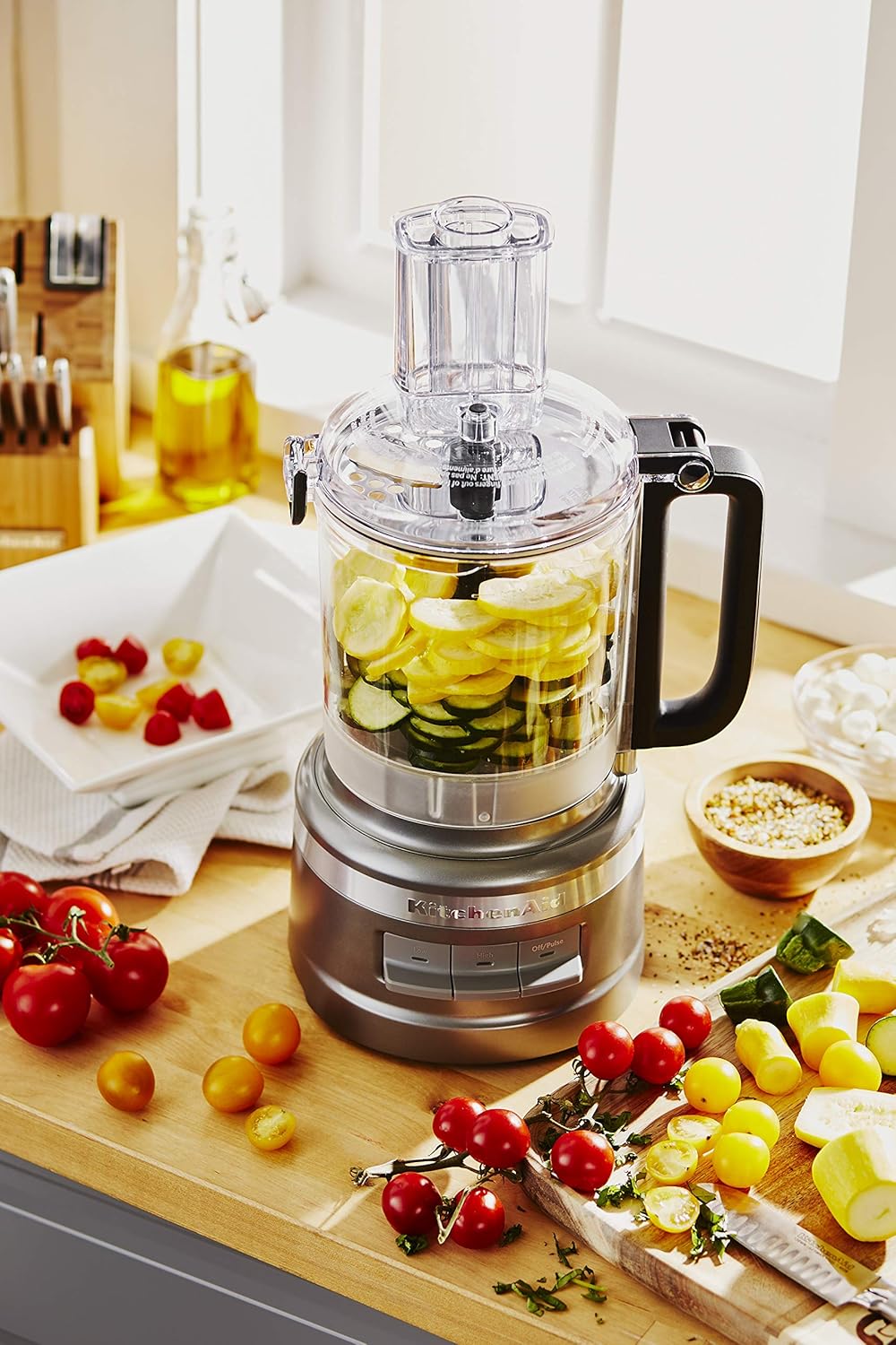 A food processor with vegetables on a counter  Description automatically generated