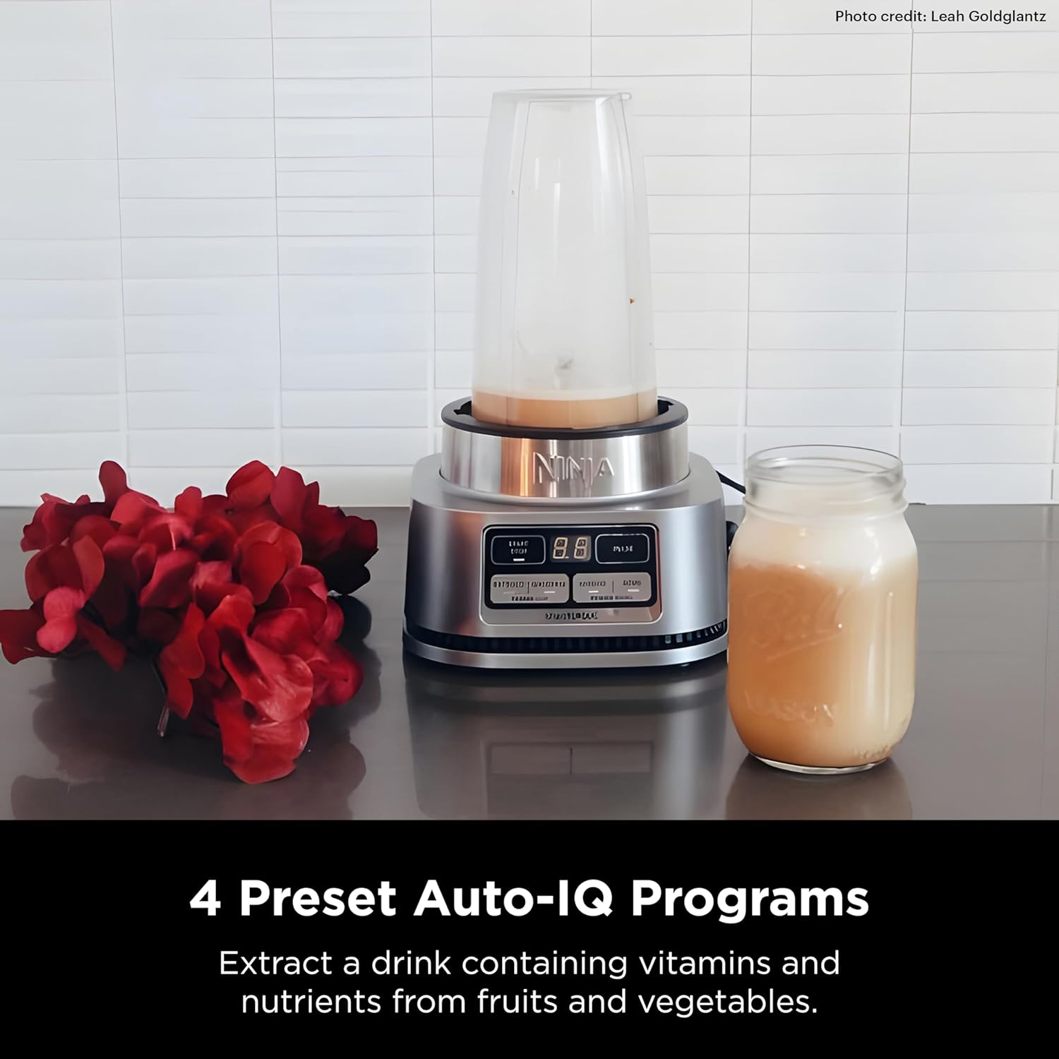 A blender with a jar of liquid next to a flower  Description automatically generated